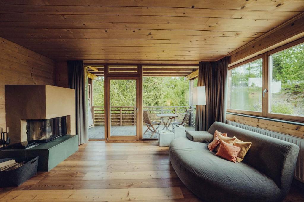 a living room with a couch and a fireplace at Holzhotel Forsthofalm in Leogang