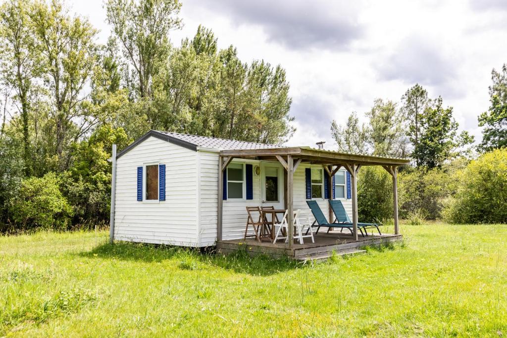 a white tiny house with a deck in a field at L'héberge du lac d'Isachris mh6 in Queyrac