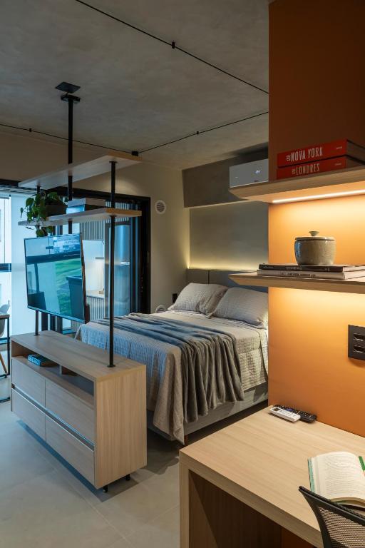 a bedroom with a bed and a desk with a television at Loft Marília City in Marília