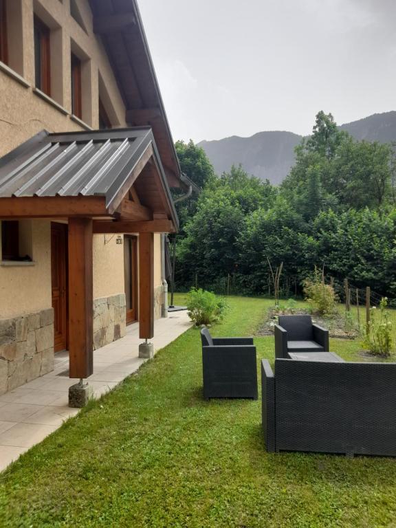un patio avec des canapés sur la pelouse à côté d'un bâtiment dans l'établissement Appartement avec jardin au pied de l'alpe d'huez, à La Garde
