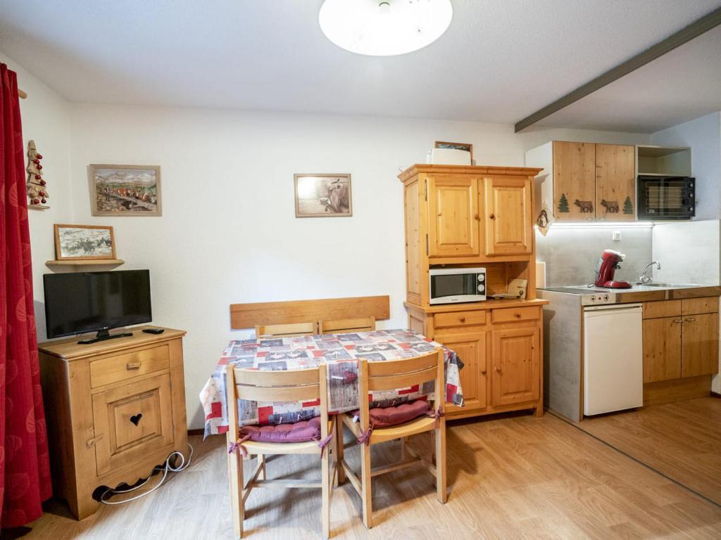 une cuisine avec une table avec des chaises et un réfrigérateur dans l'établissement Appartement cosy 2 pièces avec balcon, Châtel, proche remontées mécaniques - FR-1-676-145, à Châtel