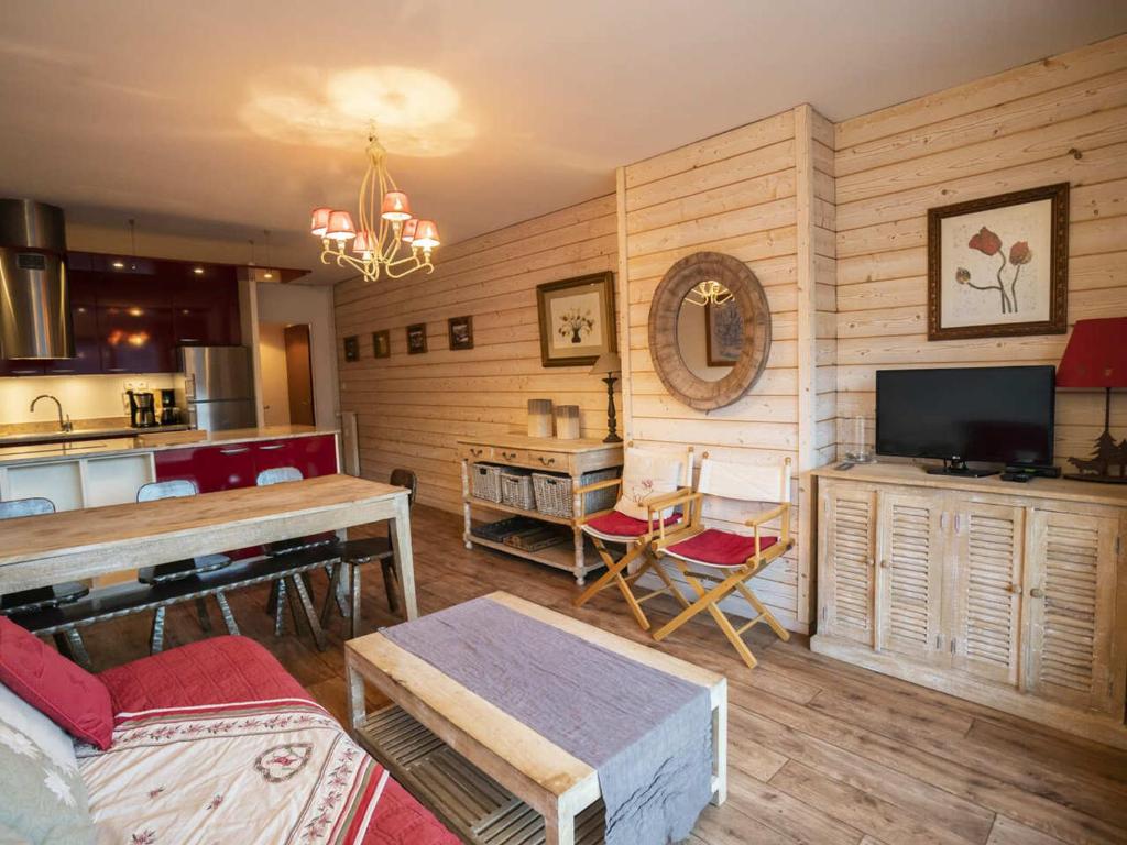 Il comprend un salon doté de murs en bois et une cuisine équipée d'une télévision. dans l'établissement Appartement cosy avec balcon, Châtel - 6 pers., proche télésiège et centre, garage inclus - FR-1-676-172, à Châtel