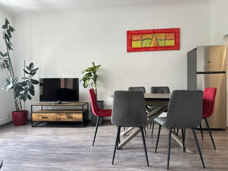 une salle à manger avec une table et des chaises et une télévision dans l'établissement #Aujé - Appart Mulhouse Centre, à Mulhouse