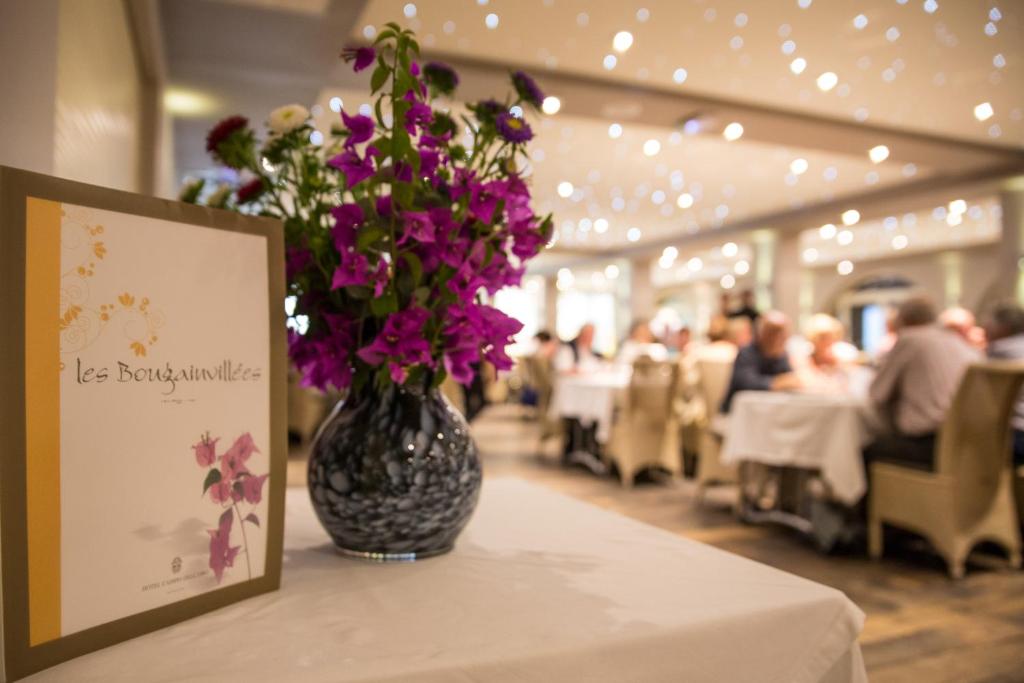 a vase with purple flowers on a table in a restaurant at Hôtel Campo Dell'oro in Ajaccio
