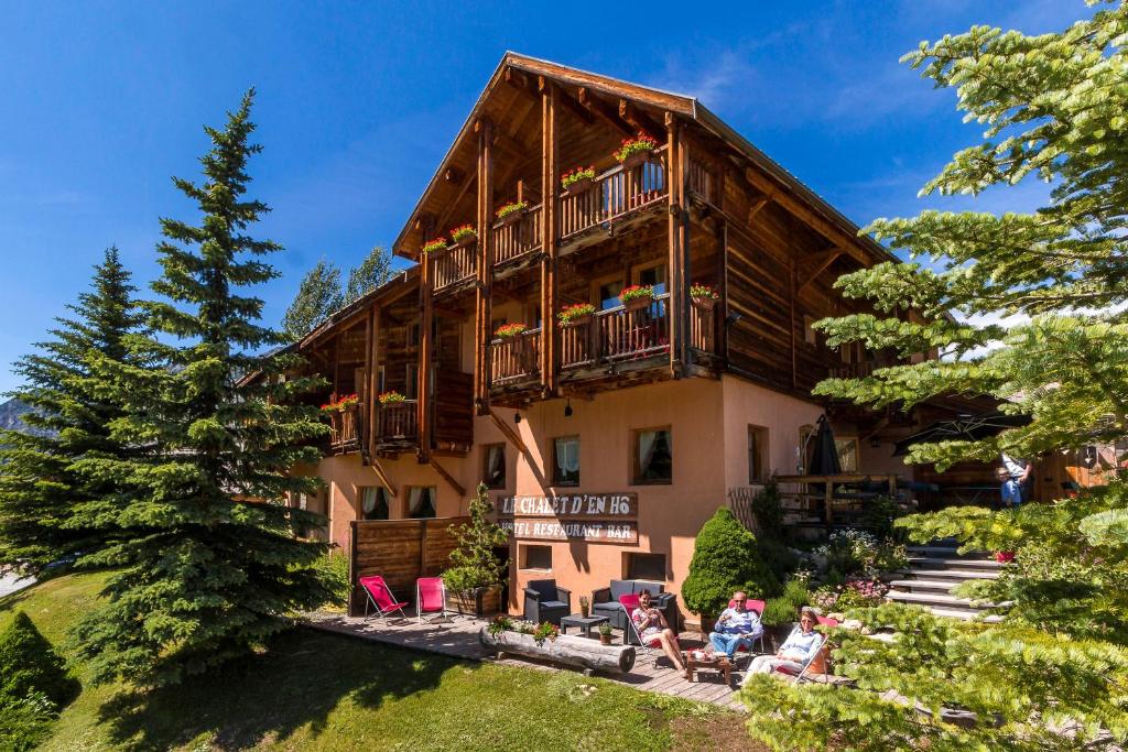 ein großes Holzhaus mit Leuten, die davor sitzen in der Unterkunft Le Chalet d'en Hô in Névache