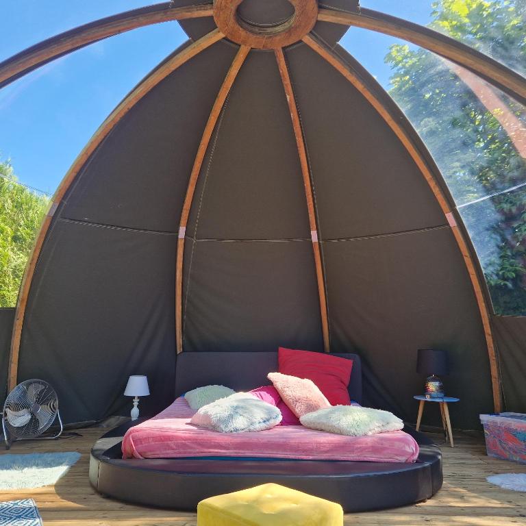 un lit dans une tente dôme avec des oreillers dessus dans l'établissement bulle de bonheur a 500 m pas de la plage, à Cancale
