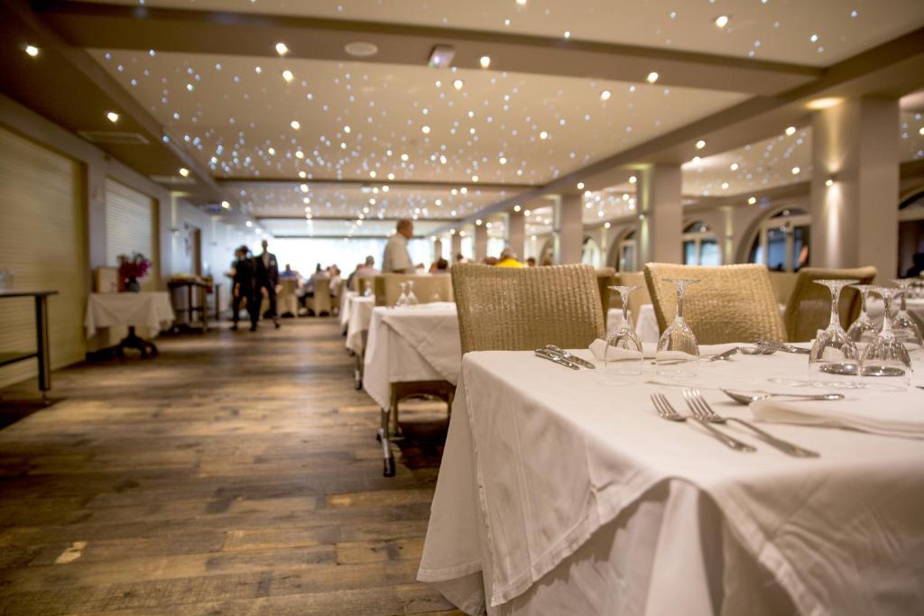 a dining room with white tables and chairs and people at Hôtel Campo Dell'oro in Ajaccio