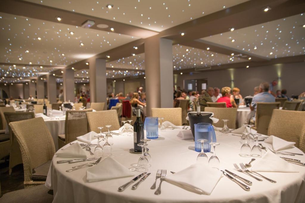 a dining room with white tables and chairs and people at Hôtel Campo Dell'oro in Ajaccio