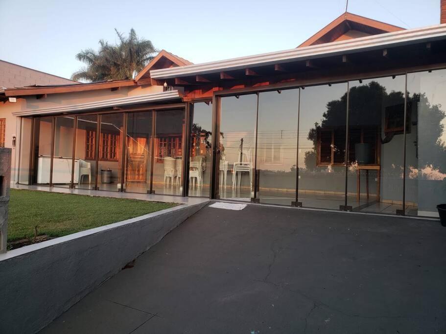 a building with large glass windows on the side of it at Casa grande com piscina Chácara do Dinho in Londrina