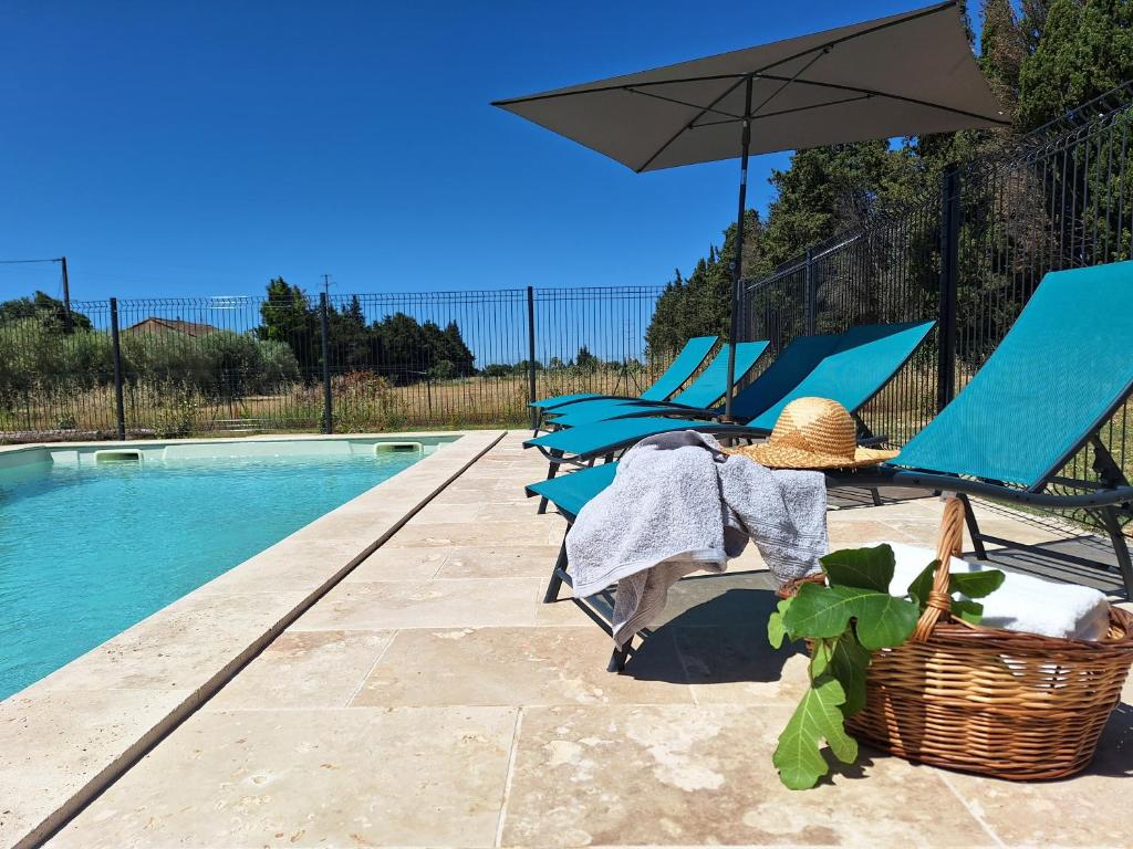 un patio avec des chaises et un parasol à côté d'une piscine dans l'établissement Mas Les Figuières, à Monteux