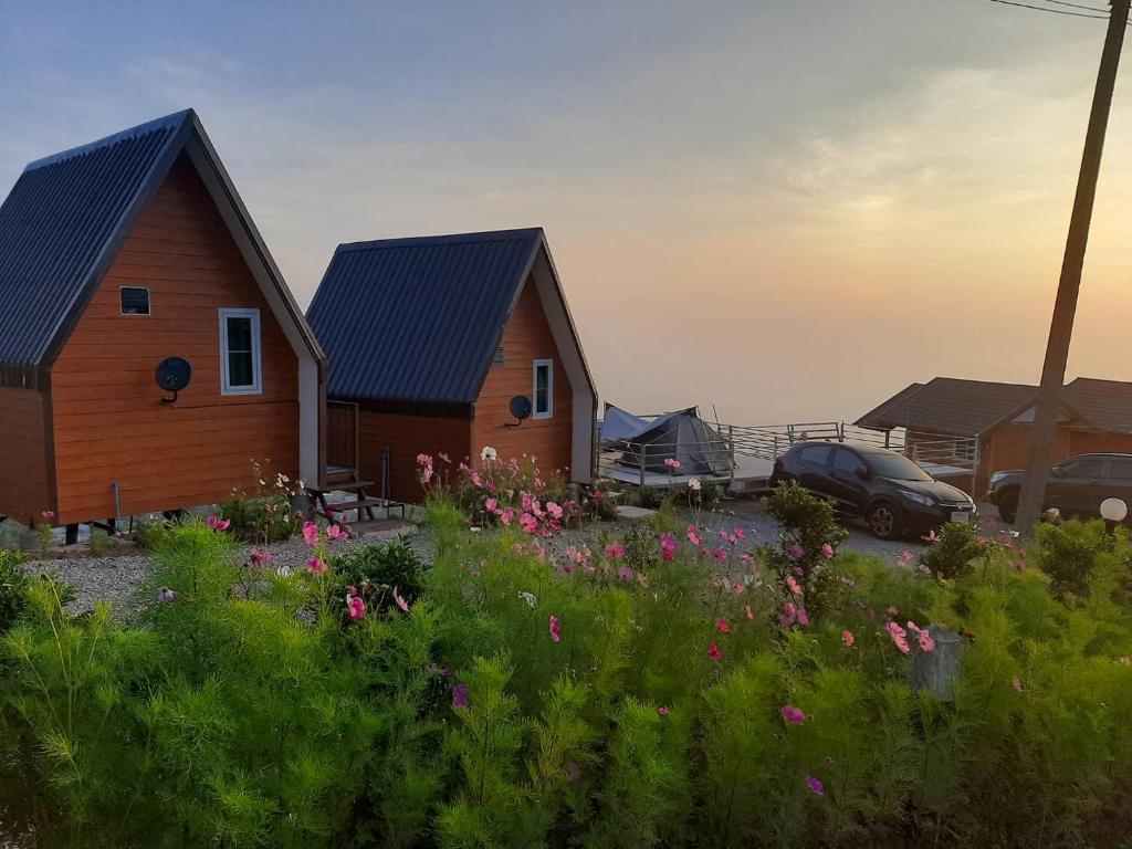 a house with a car parked next to a field of flowers at Ing Ai Mhok Phu Thap Buek in Ban Tha Kok Hai