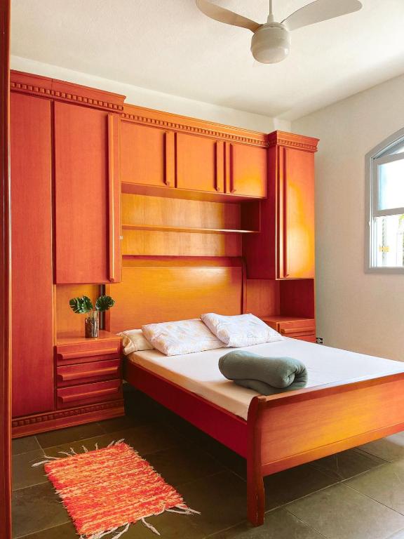 a bedroom with a large bed with wooden cabinets at Suíte Ita no Bairro Itaguá!!! in Ubatuba