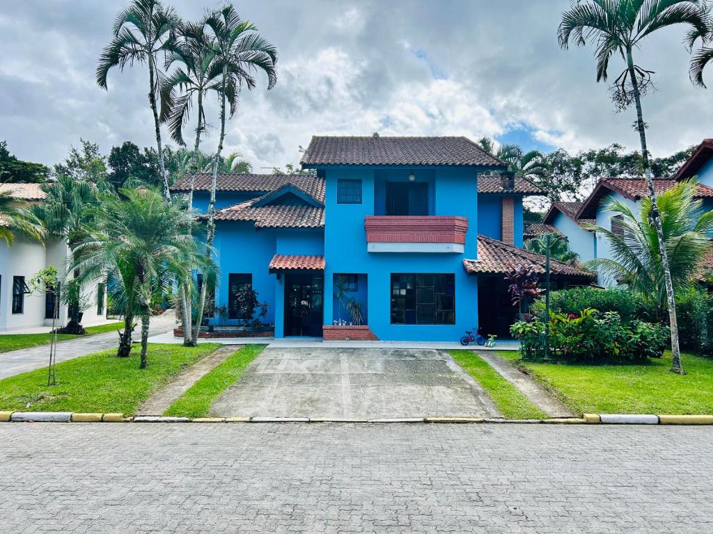 ein blaues Haus mit Palmen davor in der Unterkunft Casa de Praia Riviera de Sao Lourenco - Vilagio in Bertioga