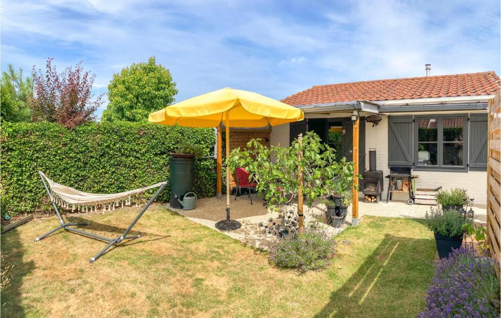 a yellow umbrella and a chair in a yard at Beautiful Home In Bredene With Kitchen in Bredene