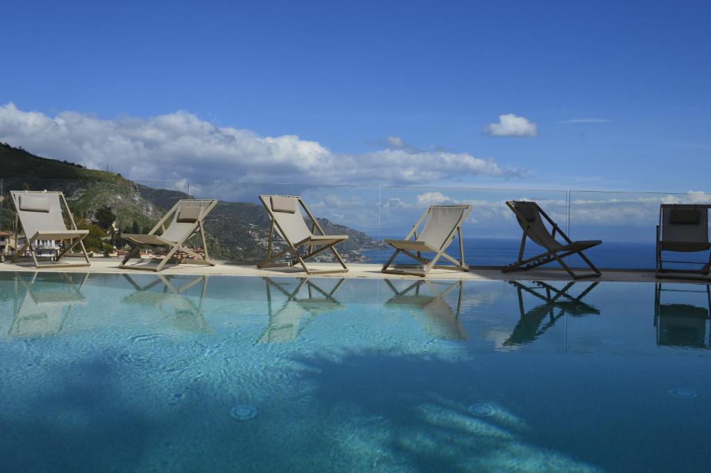 grupa krzeseł siedzących obok basenu w obiekcie Splendid Hotel Taormina w Taominie