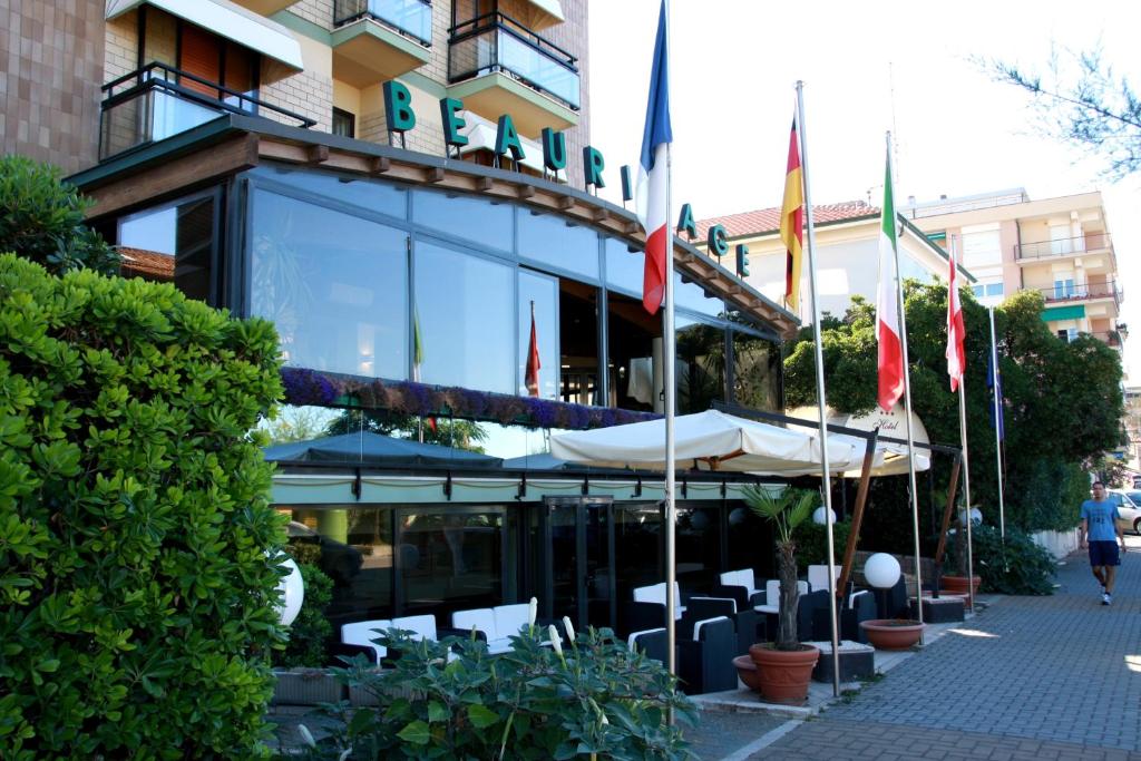 un ristorante con bandiere di fronte a un edificio di Hotel Beaurivage a Fano