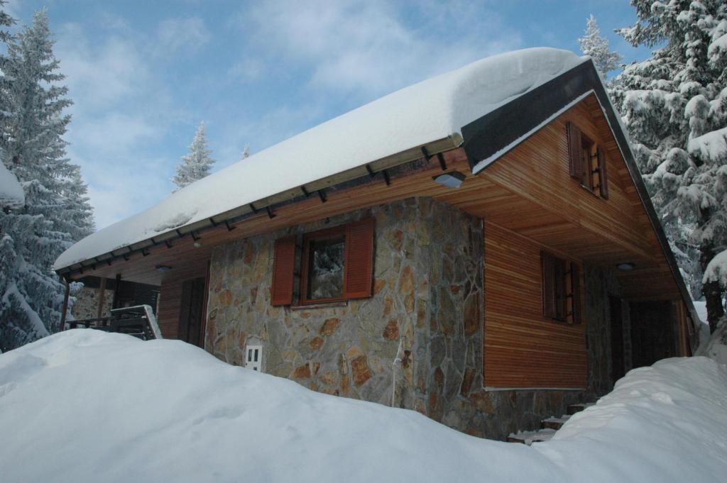 a cabin with snow on the roof in the snow at Holiday Home Cokla in Zreče