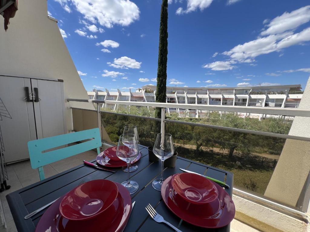 - une table avec des assiettes rouges et des verres à vin sur un balcon dans l'établissement Sol-y-Days Tropic, P2 avec vue sur jardins, à La Grande Motte