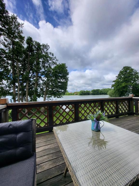 a table and a chair on a deck with a view of the water at Apartament nad jeziorem Zamkowym in Wałcz