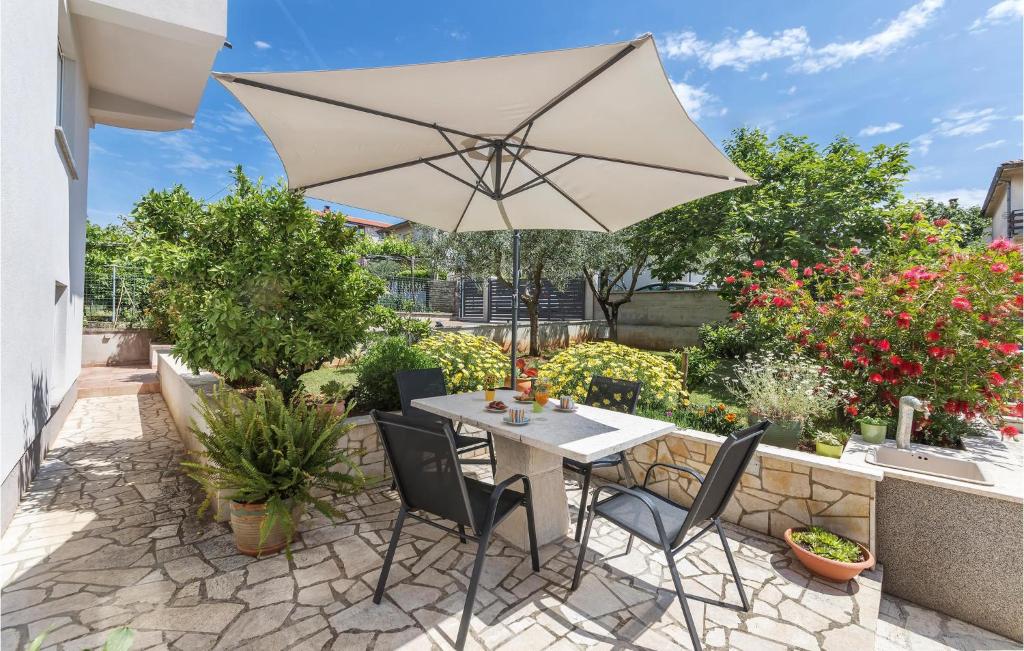 a table and chairs with an umbrella on a patio at 2 Bedroom Cozy Apartment In Pula in Veli Vrh
