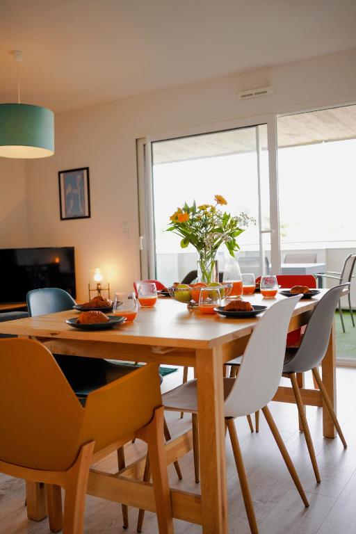 Un comedor con mesa y sillas de madera. en Lumimizan- Spacieux, grand balcon, wifi, lac et plage, en Mimizan