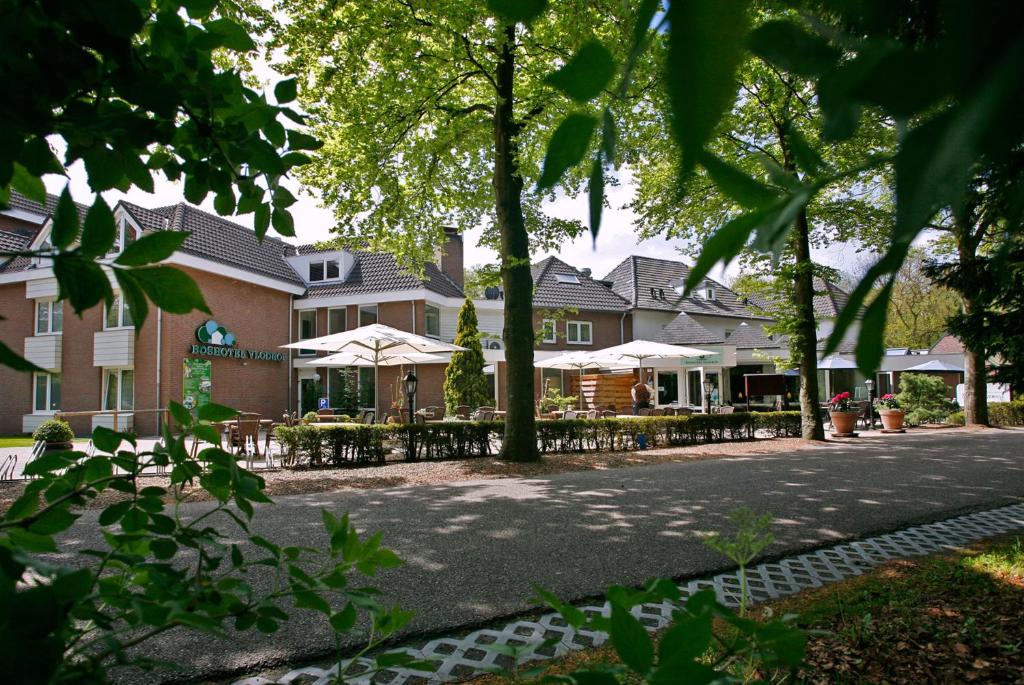 um edifício com mesas e guarda-sóis numa rua em Boshotel - Vlodrop, Roermond em Vlodrop