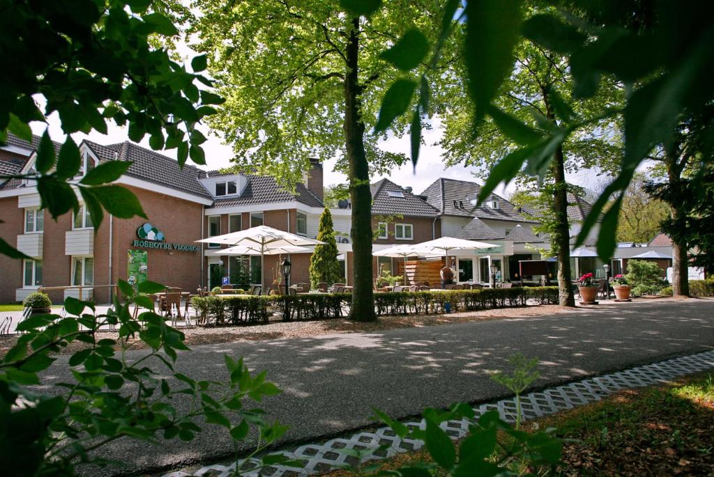 フロドロップにあるBoshotel - Vlodrop, Roermondの通りに面したテーブルとパラソルのある建物