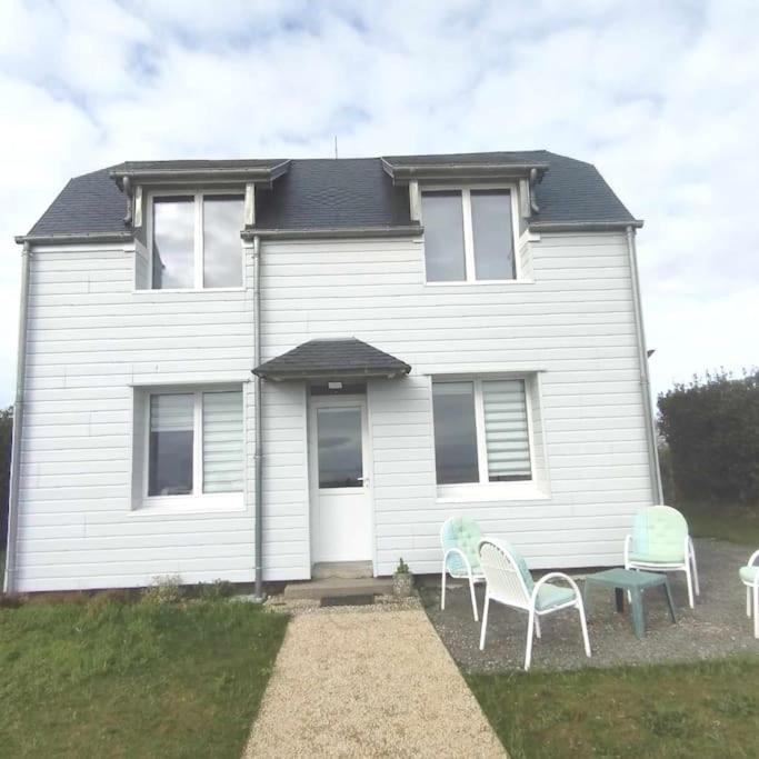 une maison avec des chaises et une table devant elle dans l'établissement L'Oeil du Mont Maison vue sur le Mont Saint Michel et sa baie, à Champeaux