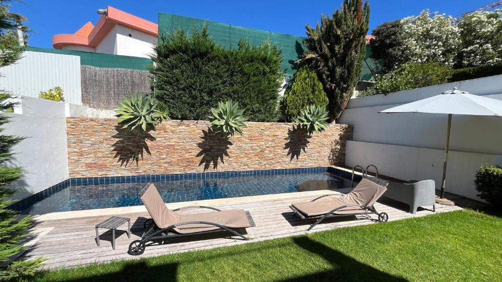 two chairs and an umbrella next to a swimming pool at Alto da Ria 37 in Alvor