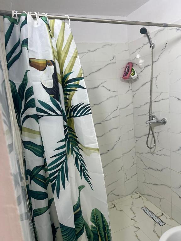 een badkamer met een douchegordijn met een tropische print bij Welcome Guest House in Shkodër