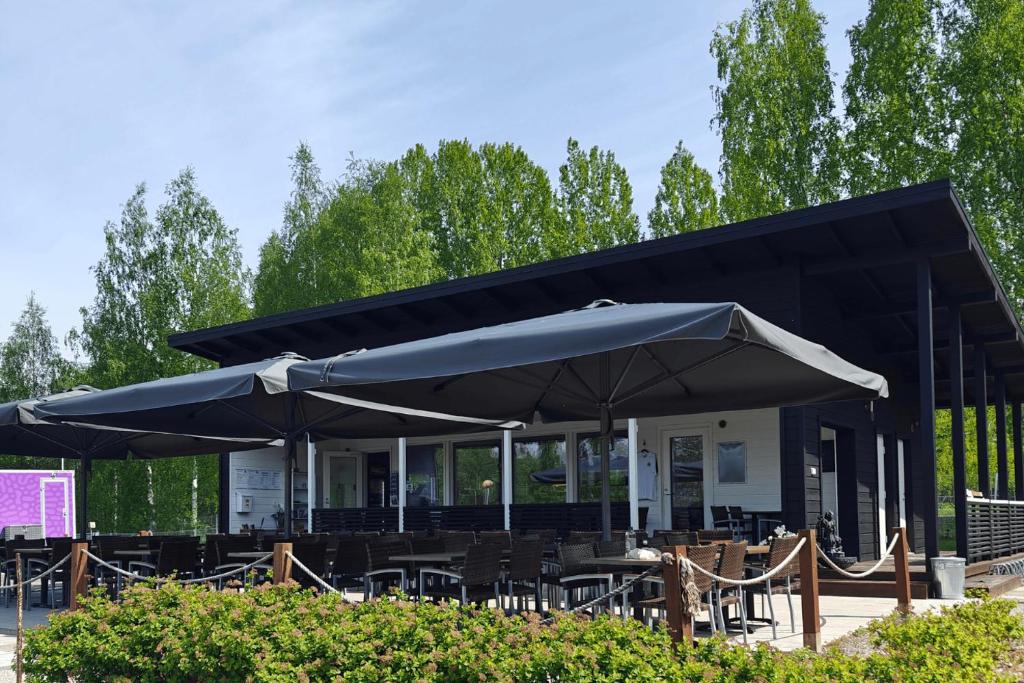 ein schwarzes Restaurant mit Tischen und Sonnenschirmen in der Unterkunft Vuohimäki Camping Savonlinna in Savonlinna