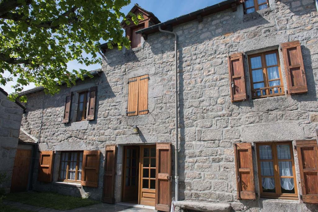 - un vieux bâtiment en pierre avec des portes et des fenêtres en bois dans l'établissement Gîte Gîtes de France 6/7 personnes au Fau de Peyre, à Fau-de-Peyre