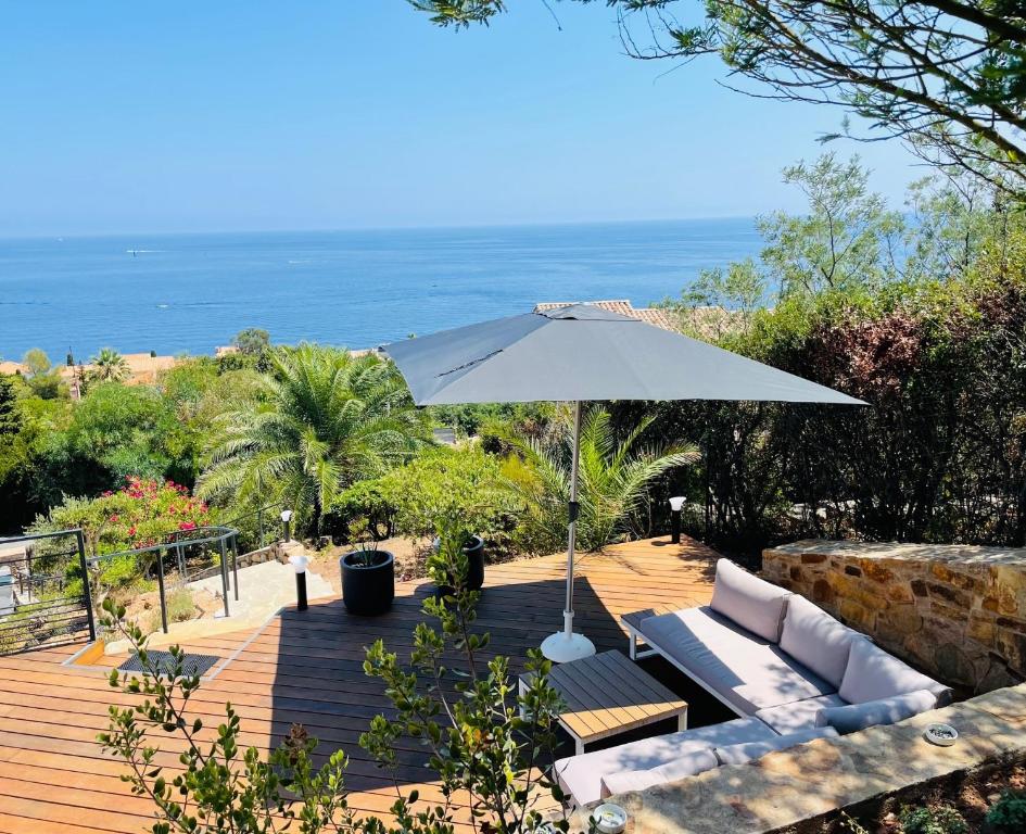 une terrasse avec un parasol blanc, un canapé et des chaises dans l'établissement Superbe vue mer et Estérel, Villa Neuve pour 8-10 Personnes, Clim, Piscine, à Saint-Raphaël