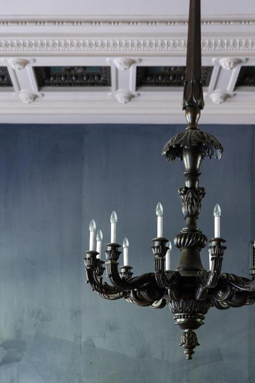 a black chandelier with white candles hanging from a ceiling at The Benjamin House in Rīga
