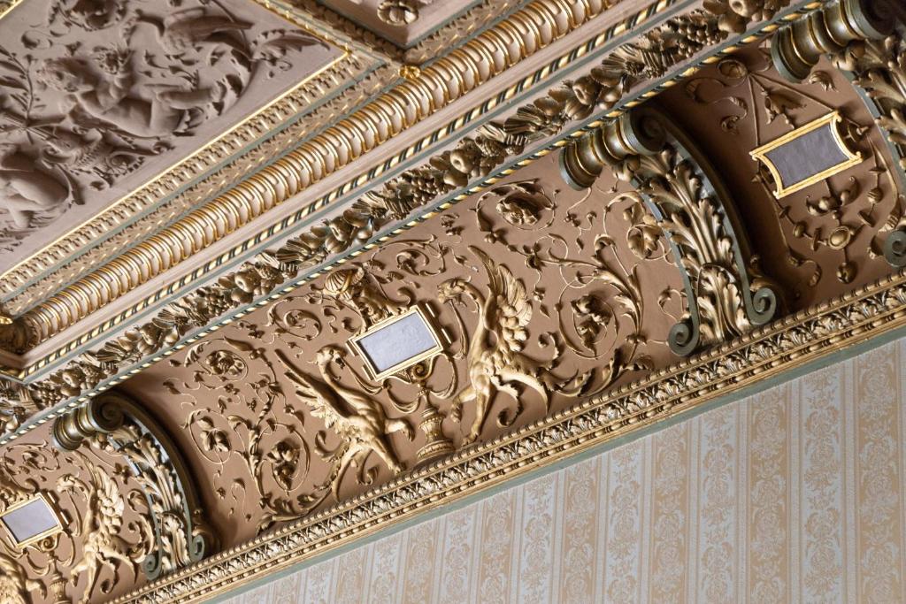 an ornate ceiling of a building with gold paint at The Benjamin House in Rīga