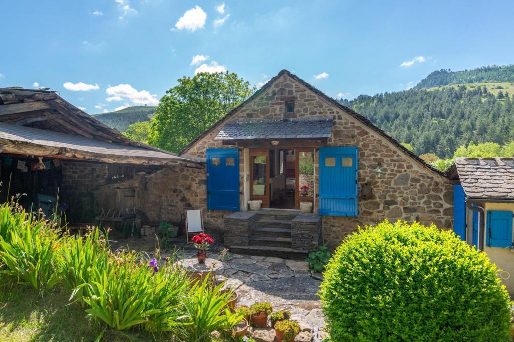 une maison en pierre avec des portes bleues dans une cour dans l'établissement Gîte Gîte Les Combettes 2/3 personnes, à Ispagnac
