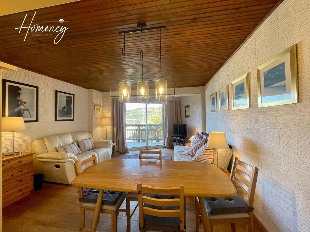 a living room with a wooden table and a couch at Homency - Résidence de l'Alpe 23 in L'Alpe-d'Huez