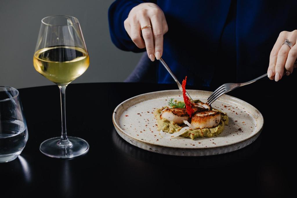 a person eating a plate of food with a glass of wine at Vale d'El Rei Hotel & Villas in Carvoeiro