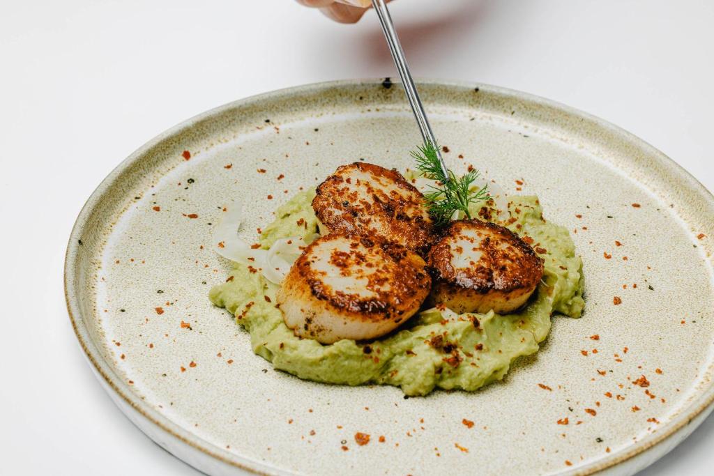 a plate of food with shrimp on top of green sauce at Vale d'El Rei Hotel & Villas in Carvoeiro