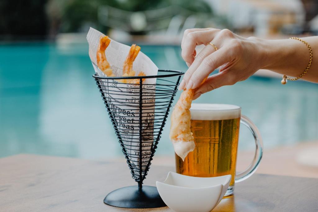 a woman eating french fries and a mug of beer at Vale d'El Rei Hotel & Villas in Carvoeiro