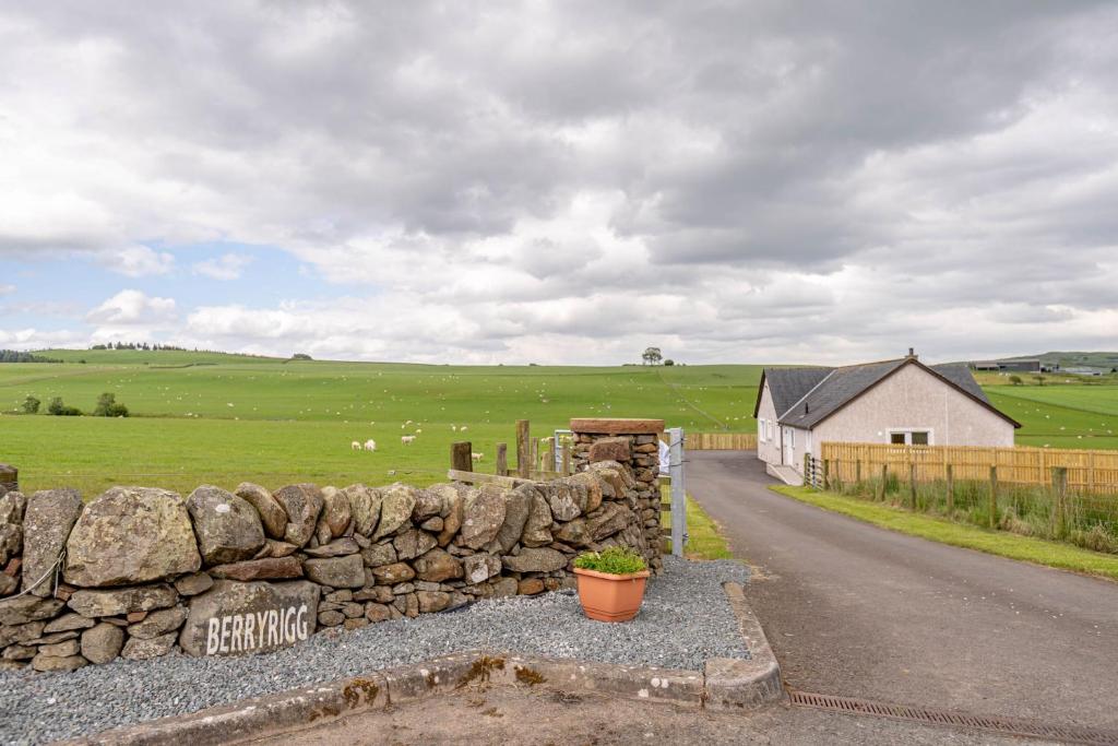 un muro di pietra accanto a una strada in un campo di Berryrigg Cottage a Dumfries