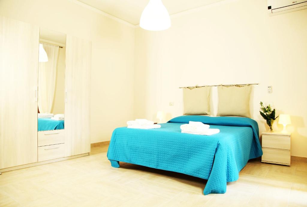 a white bedroom with a blue bed and a mirror at Casa A Riba U Mari in Riposto