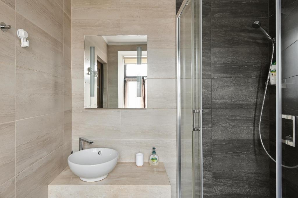 Modern Studio-apartment in the centre في ريغا: حمام مع دش ومغسلة ومرآة