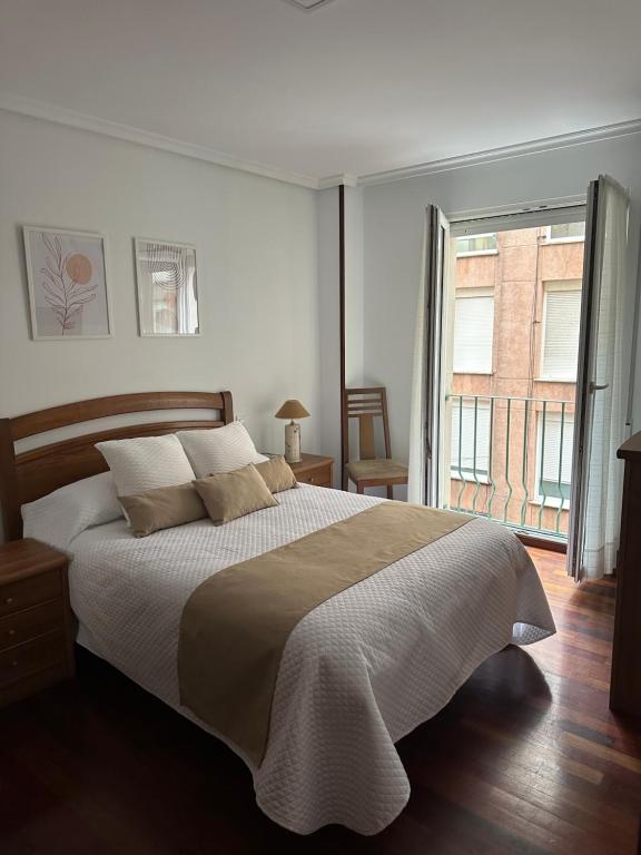 a white bedroom with a large bed and a window at Vivienda vacacional: Los Abuelos in San Vicente de la Barquera