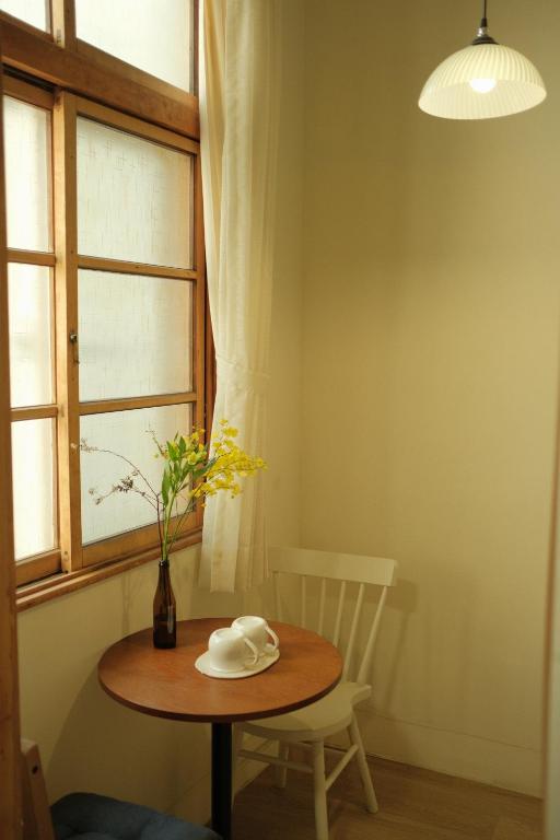 a table with a vase of flowers and a window at Maru in Tainan