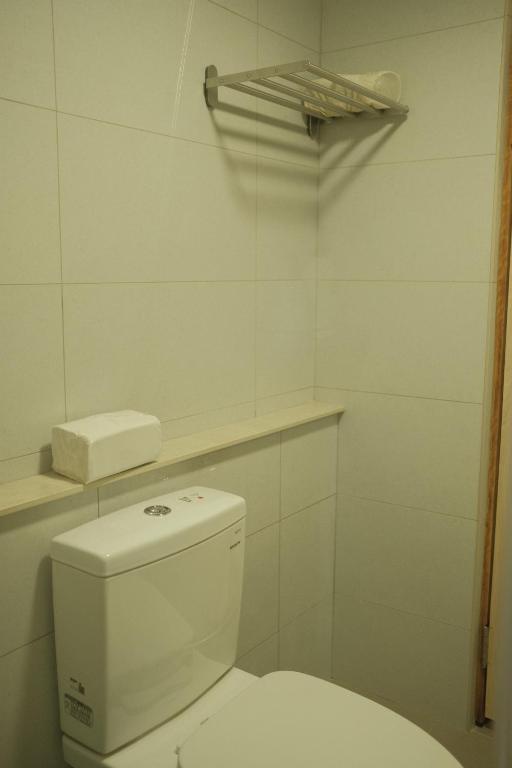 a white bathroom with a toilet and a shelf at Maru in Tainan