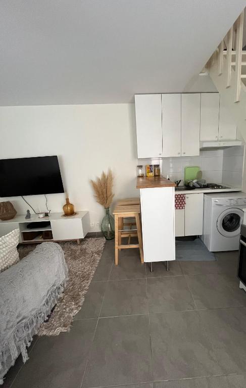 une cuisine avec des armoires blanches et une table dans une pièce dans l'établissement Maisonnette à 10 minutes de Paris - La Défense, à Suresnes