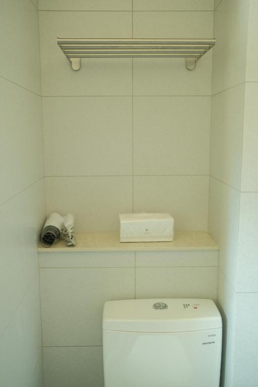 a bathroom with a toilet with a shelf above it at Maru in Tainan