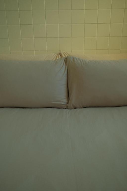 a white bed with two pillows on top of it at Maru in Tainan