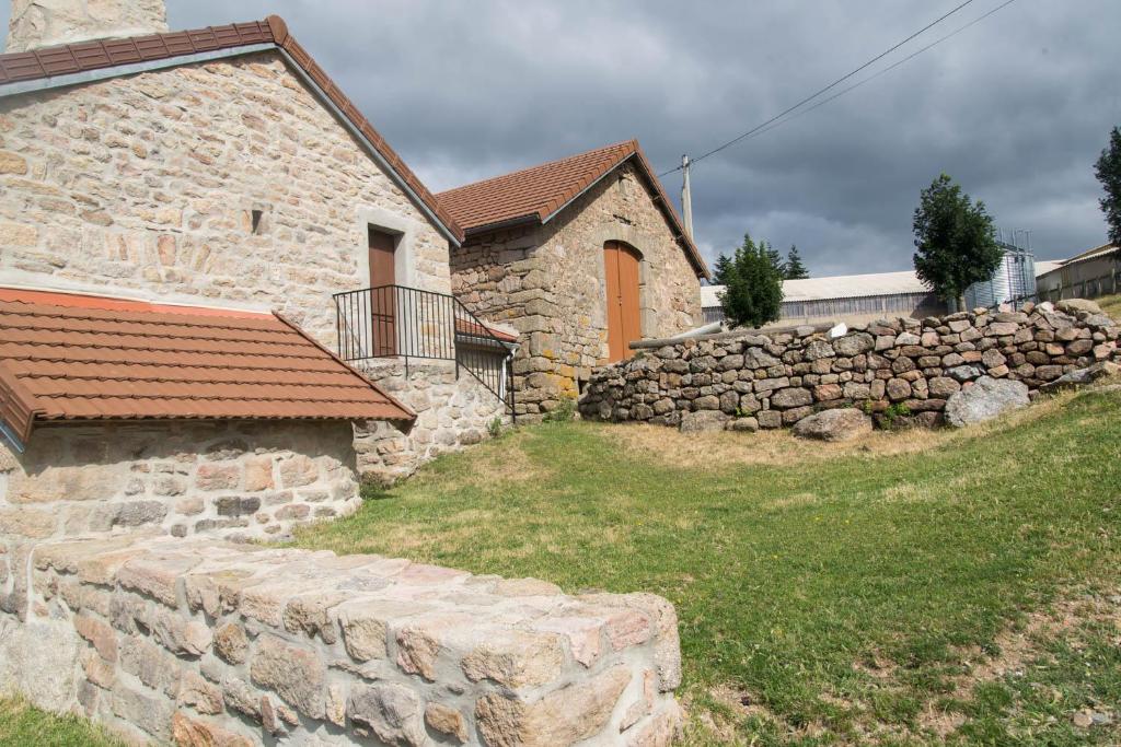 un bâtiment en pierre avec un mur en pierre à côté d'une maison dans l'établissement Gîte Gîtes de France 3/5 personnes à La Bessière, à Saint-Jean-Chazorne